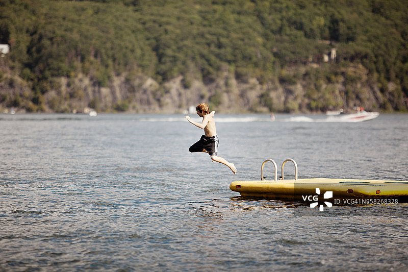 男孩跳入山边的湖中图片素材