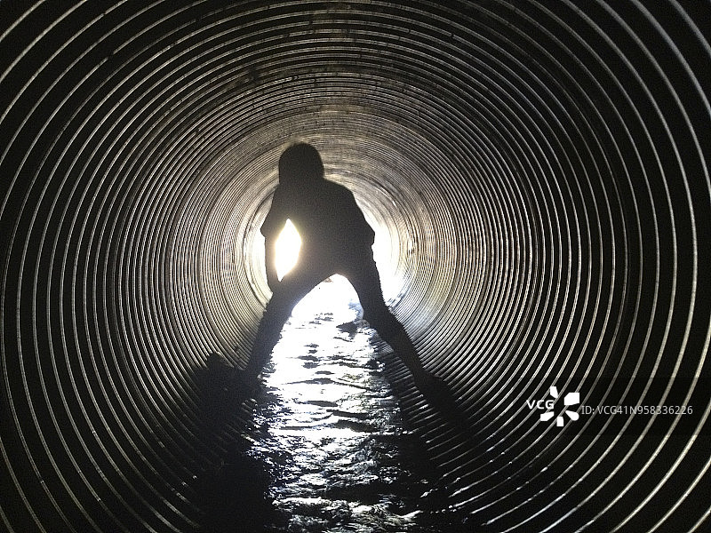 站在污水隧道中的男孩背影图片素材