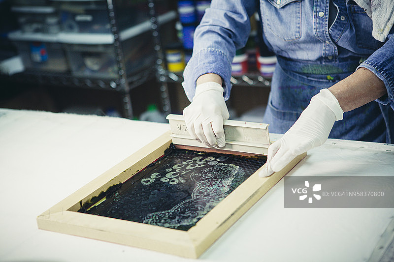 女手工艺人用刮刀在织物上印刷图案图片素材