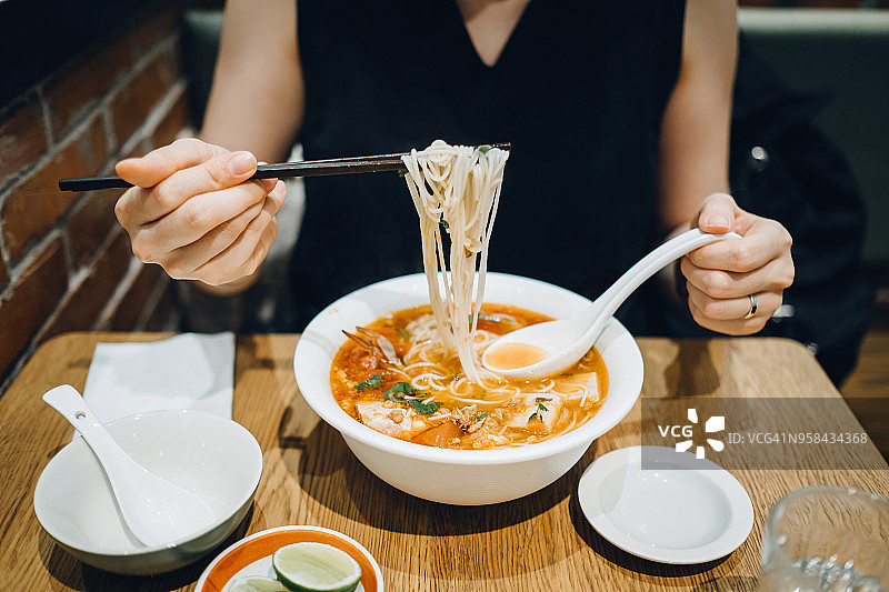 女子在餐厅用筷子高兴地吃面条特写图片素材