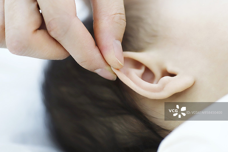 母亲的手触摸婴儿的耳朵图片素材