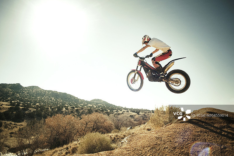 男人在晴朗的天空下用摩托车表演特技的侧视图图片素材