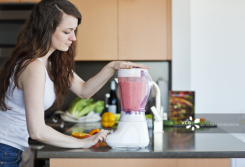 女人在家准备果汁的侧面视角图片素材