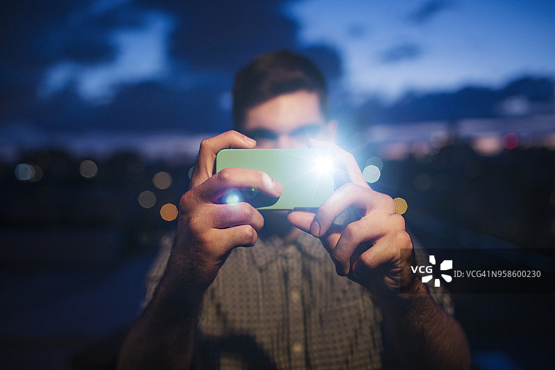 男人站在建筑物露台上，在黄昏时对着多云的天空拍摄图片素材