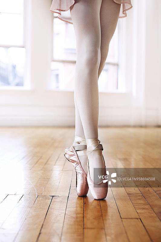 芭蕾舞老师在硬木地板上踮起脚尖的下半身图片素材