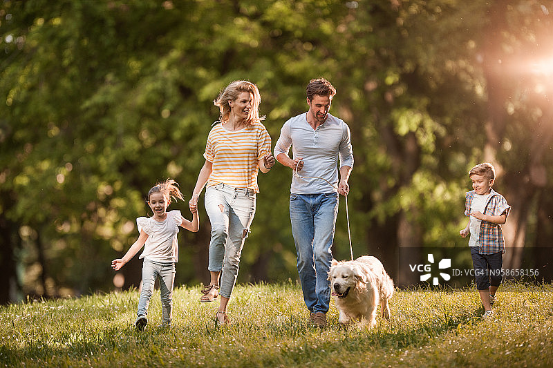 幸福的一家人在公园里和狗一起奔跑玩耍图片素材