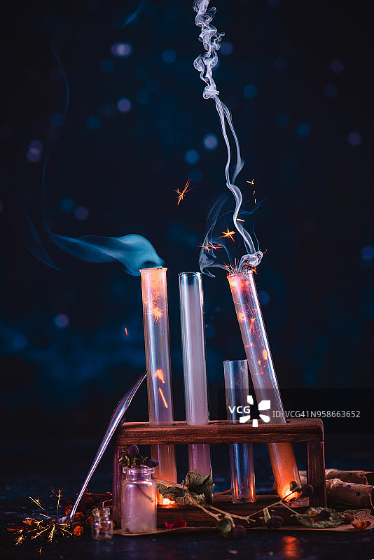 科学实验与试管在木制支架上升起的烟雾，火光和火花。与复制空间的魔法静物。在黑暗背景下的炼金术概念。图片素材