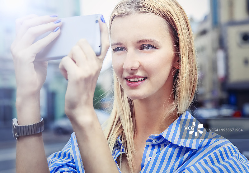女孩在城市户外用智能手机拍摄图片素材