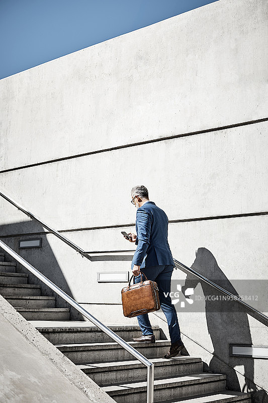 在台阶上使用手机的中年商人图片素材