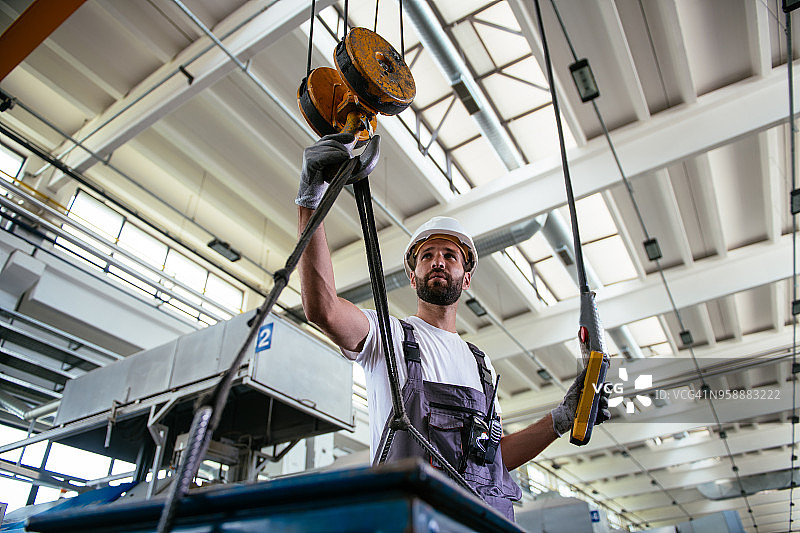 工厂里使用起重梁的年轻男工程师图片素材