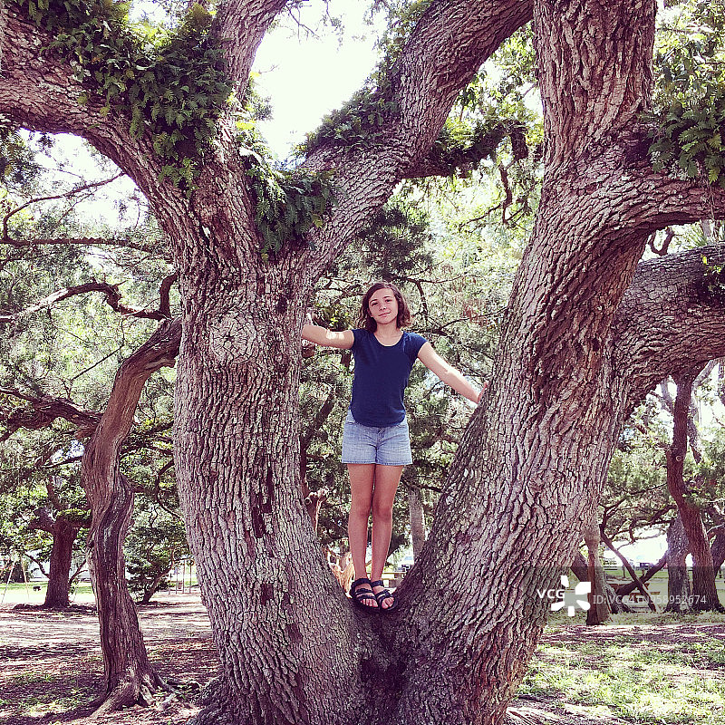 站在扭曲的活橡树上的女孩图片素材