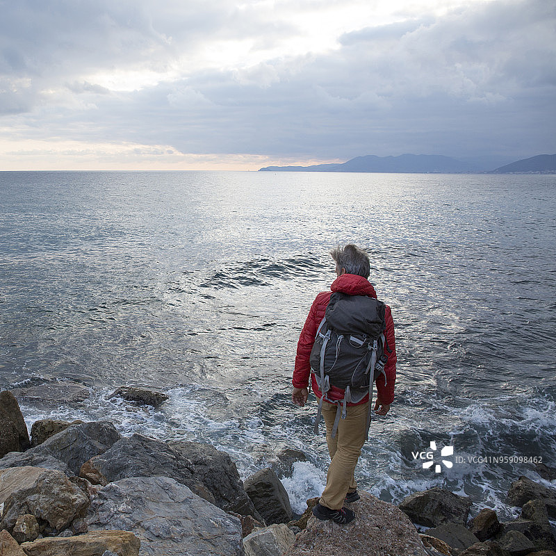 中年男人探索多石海岸和大海图片素材