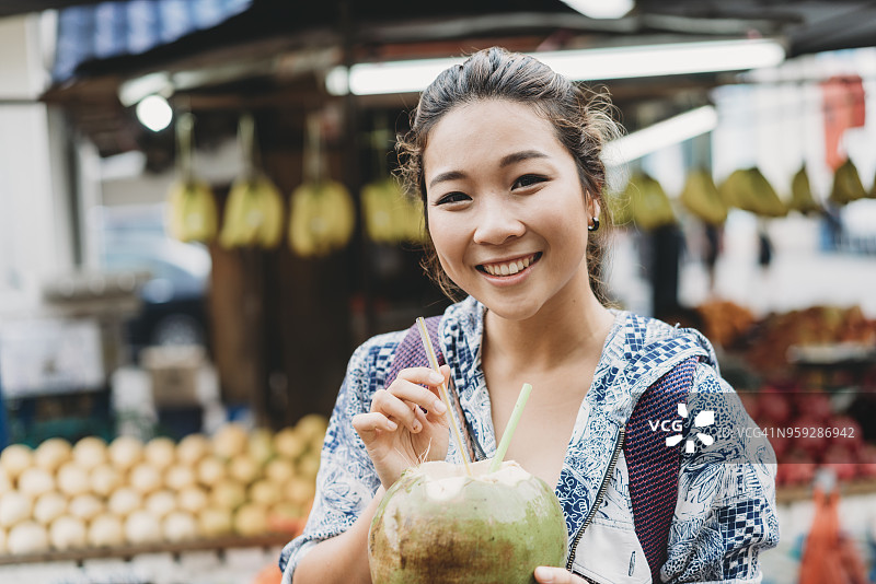 在市场喝椰汁的年轻女子图片素材