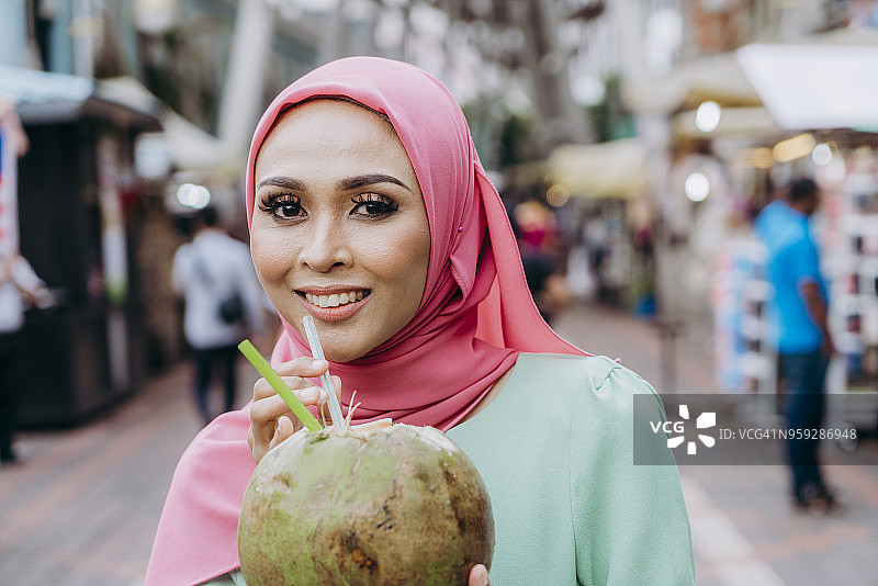 在市场喝椰汁的年轻女子图片素材