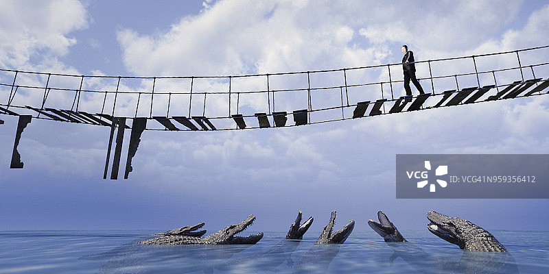 商人走过危险的绳索桥，向下看着水中的鳄鱼图片素材
