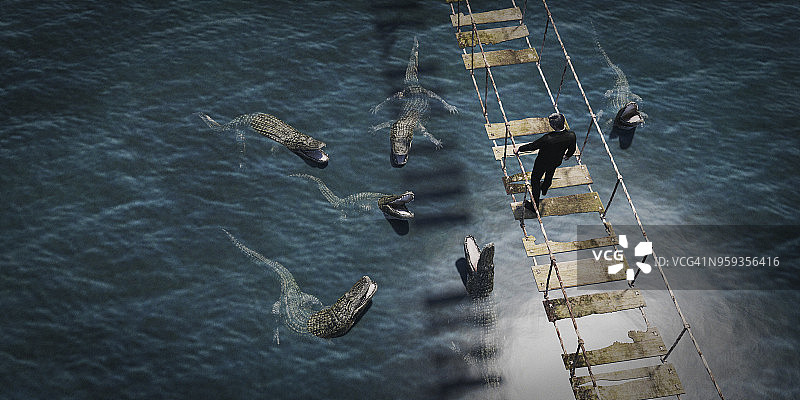 商人走过危险的绳索桥，向下看着水中的鳄鱼图片素材