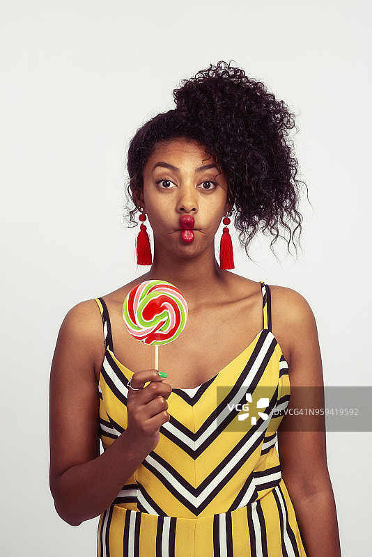 女人做鬼脸，拿着彩色漩涡棒棒糖图片素材
