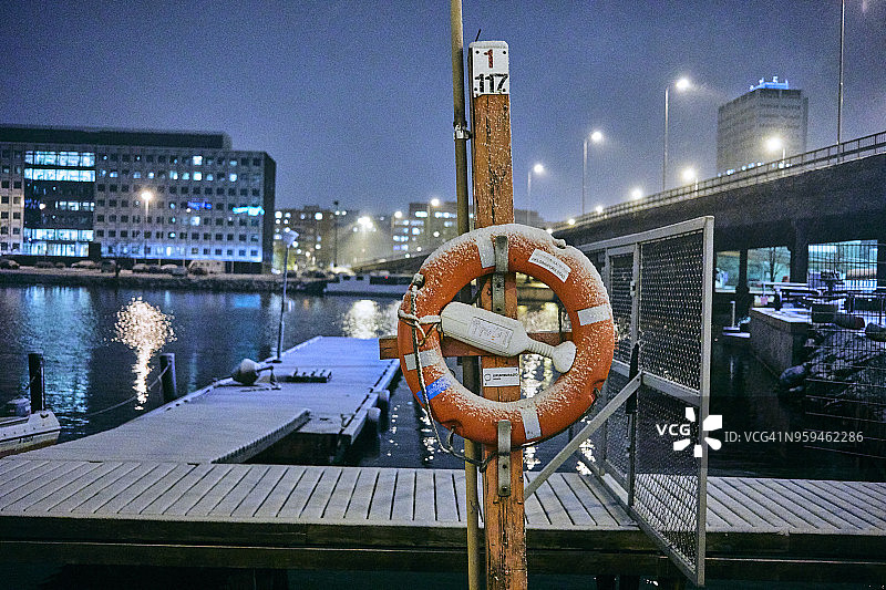 薄雪覆盖的赫尔辛基海湾救生圈和木码头夜景图片素材