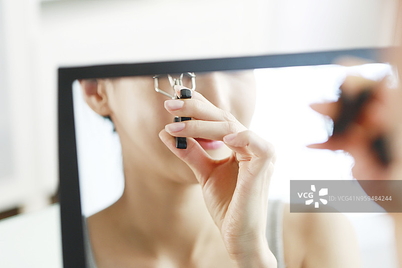 使用睫毛夹的年轻女人图片素材