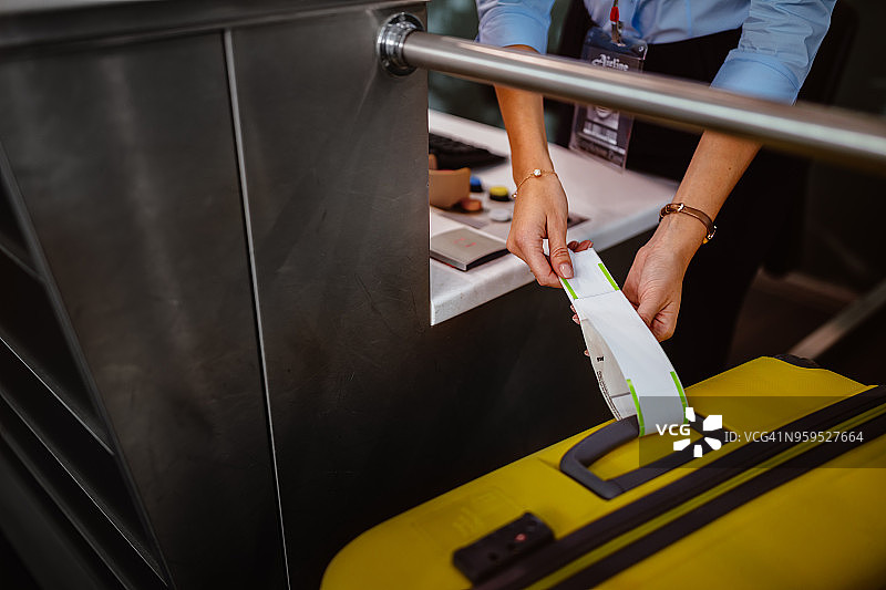 机场办理登机手续柜台员工在行李上贴标签图片素材