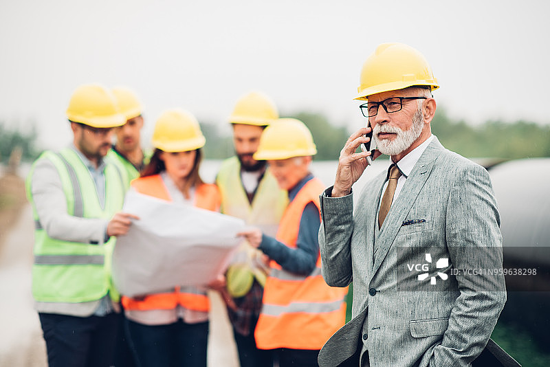 在建筑工地上打电话的老年商人图片素材