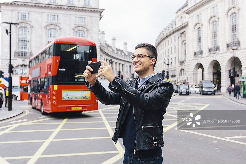快乐的年轻人在英国伦敦皮卡迪利广场用智能手机拍照图片素材