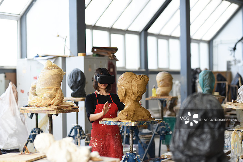 年轻女雕塑家在工作室使用VR图片素材