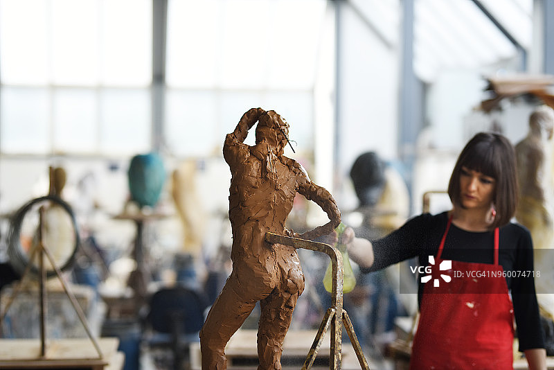 年轻女雕塑家在工作室工作图片素材