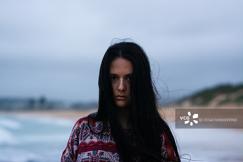 年轻女人傍晚在海滩上，正面视角图片素材