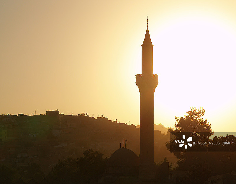 土耳其尚勒乌尔法（乌尔法）日落时分里兹瓦尼耶清真寺的宣礼塔轮廓图片素材