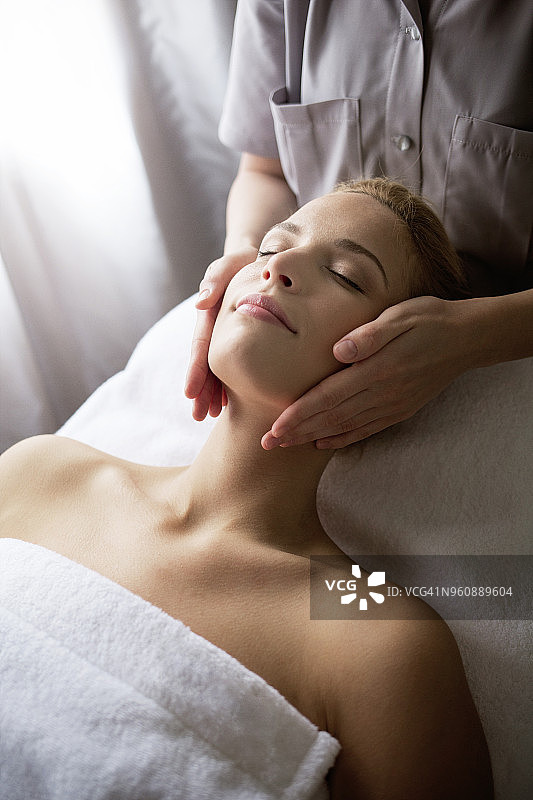 女治疗师在水疗中心为女子面部按摩图片素材