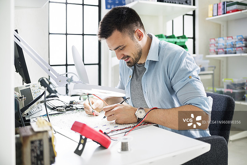 在电子实验室焊接电路板的微笑技术员图片素材