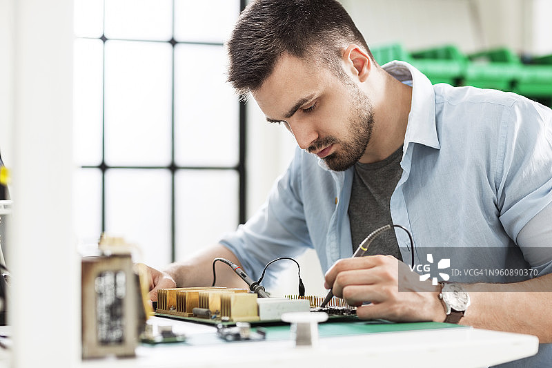 电子行业中严肃的技术人员在桌子上焊接电路板图片素材