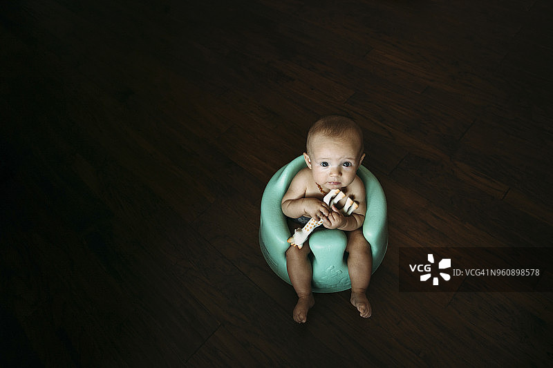 宝宝坐在家里的便盆上玩玩具（高角度拍摄）图片素材