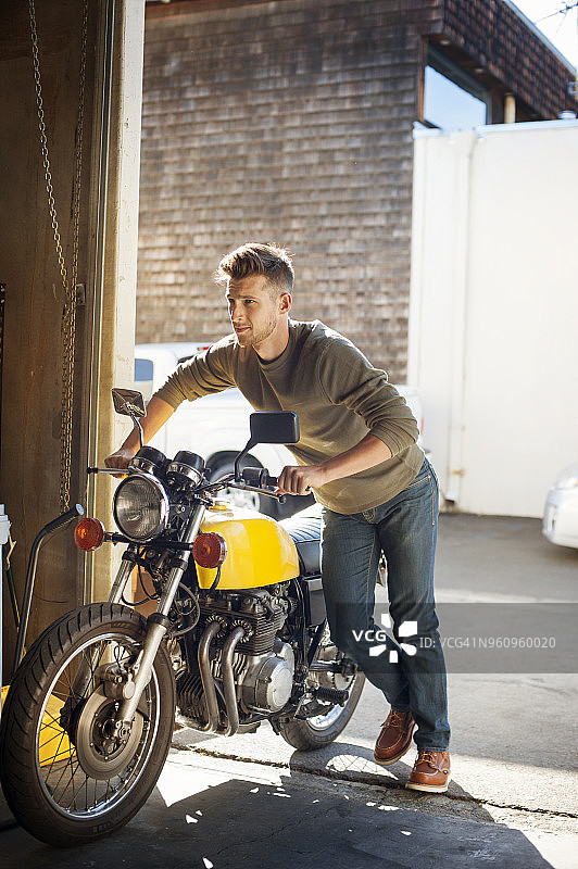 男人在车库里推动摩托车图片素材