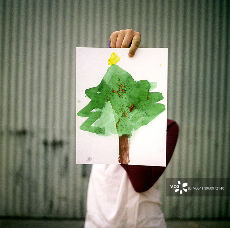 男孩拿着绘画挡住脸图片素材