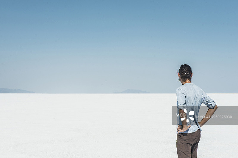 男子站在盐滩上，背景是晴朗的蓝天图片素材