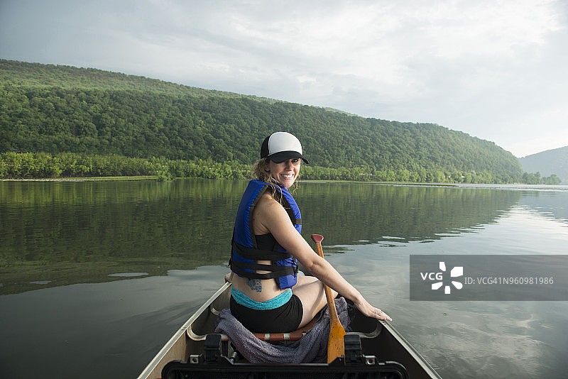 阴天，在河上划独木舟的微笑女性肖像图片素材