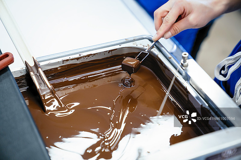 女厨师用叉子在巧克力火锅中蘸巧克力图片素材