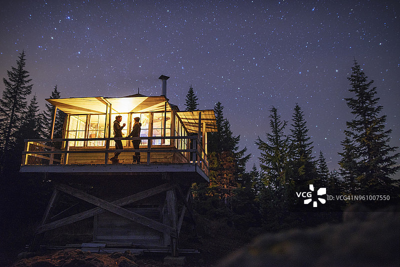 仰视角度：夜晚，女子们站在灯火通明的小屋里图片素材