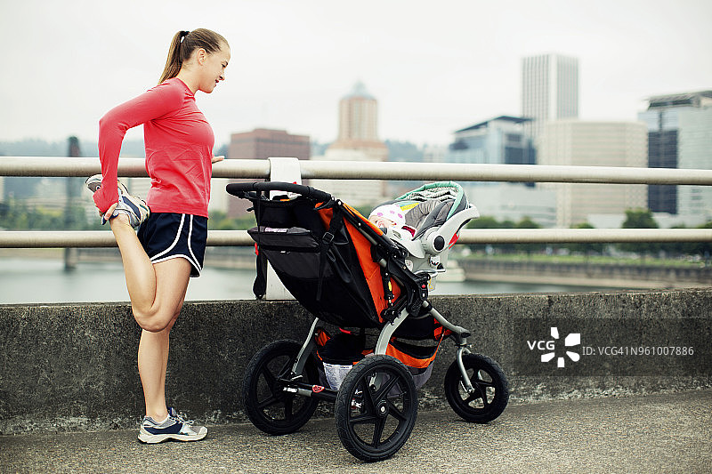 女子在城市人行道上，在婴儿车旁伸展身体图片素材