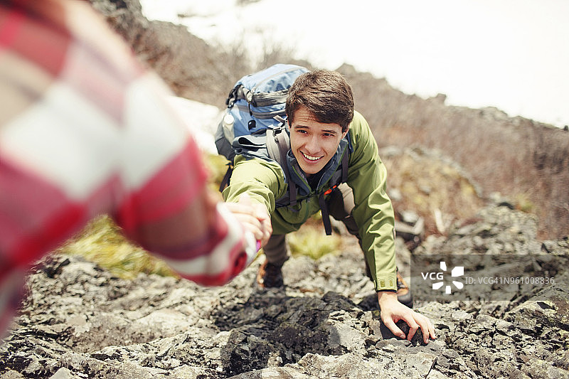 女人帮助男性朋友爬山图片素材