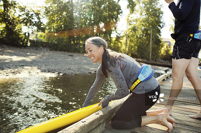 女人将桨板放在河上，男人站在码头旁图片素材