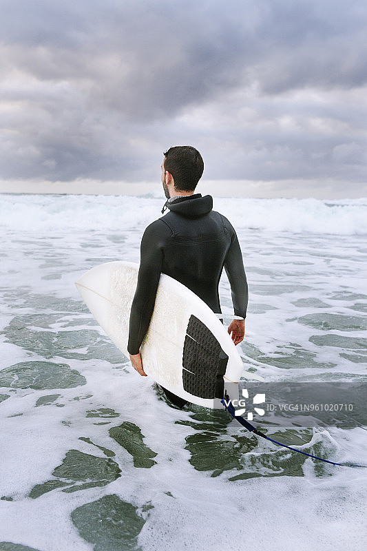 男子在海边扛着冲浪板的背影图片素材