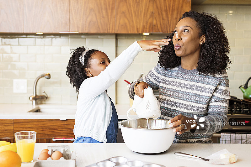 母女在厨房用电动搅拌器混合面糊图片素材