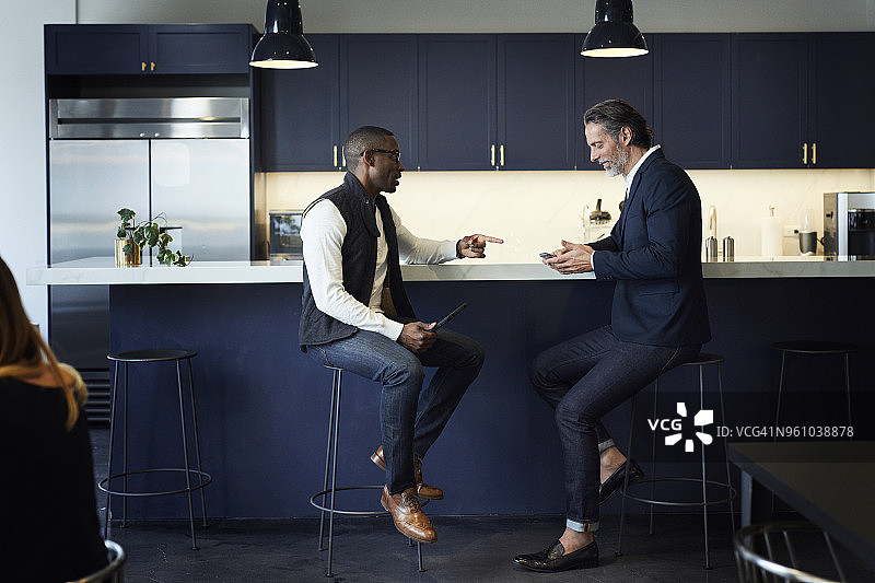男同事们坐在创意办公室的厨房吧台上交谈图片素材