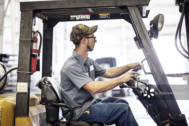 侧面视角：工人在金属钢铁厂驾驶叉车图片素材
