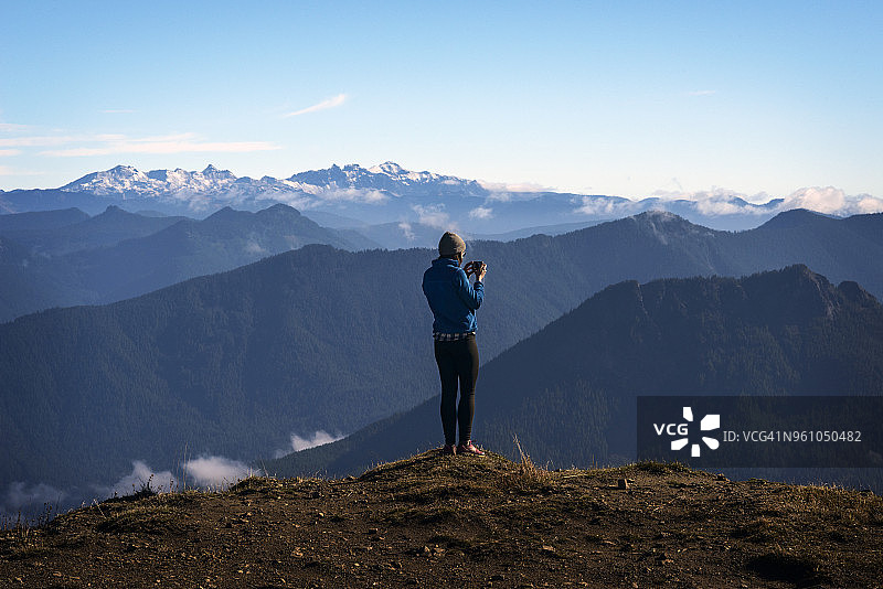 女子在悬崖边拍摄山景的背影图片素材
