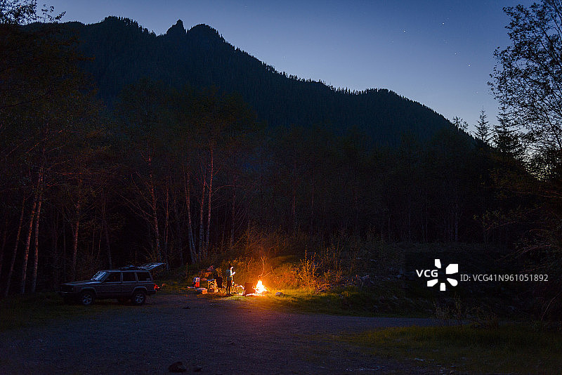 徒步者在黄昏时分于山间营地篝火旁露营图片素材