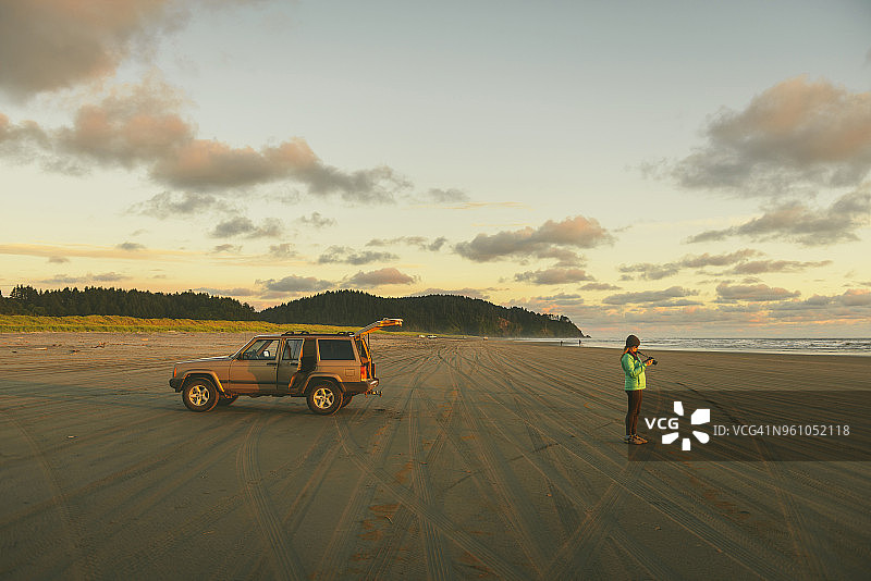 女徒步旅行者在长滩手持相机的侧视图图片素材